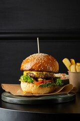 Close up of burger on black table and potato fries
