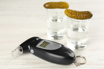 Modern breathalyzer and vodka with pickles on white wooden table