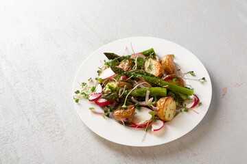 Potato radish and asparagus salad on white plate