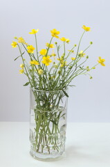 Bouquet of yellow flowers in glass, white background, vertical picture