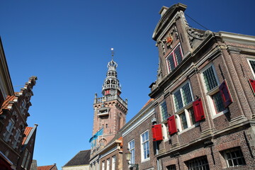Historic house facades located at the harbor of Monnickendam, North Holland, Netherlands, with the spire and clock tower of Speeltoren (The Carillon) 