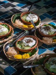 Group of colorful Thai desserts in a bamboo basket and pottery cup. Thai food, Thai dessert, or sweets. Food and drink concept.