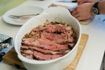 Midsection of man cutting roast meat on table at kitchen