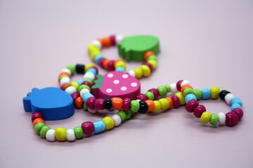 A bracelet made of beads on a pink background.