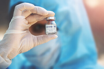 A doctor in medical gloves and mask holding an coronavirus vaccine. Coronavirus, epidemic and medicine concept.