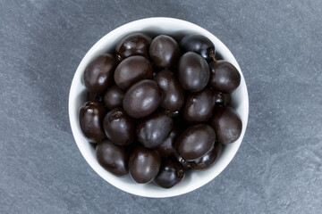 Black olives from above bowl on a slate