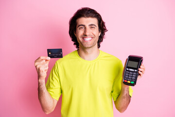 Photo of happy handsome young man hold credit card terminal cheerful smile isolated on pink color background
