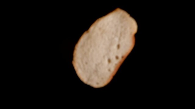 Sliced white bread falling into dark background in slow motion.