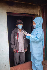 Young woman doctor in medical uniform holding a syringe and coronavirus vaccine, standing with village men explaining importance of corona virus vaccine