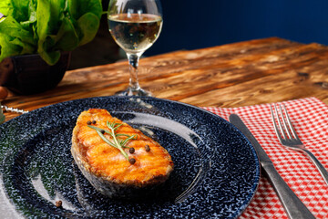 Grilled salmon steak on blue plate on wooden table