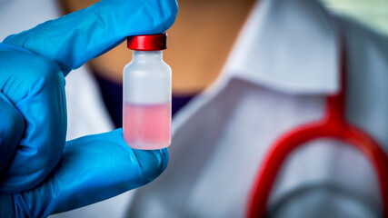Doctor or scientist carries a vial of liquid vaccine for children and adults to test for COVID-19...