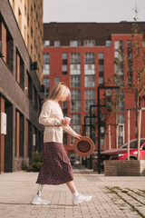 Girl with a bionic prosthesis walks at the house, holding a coffee and a hat in her hand.