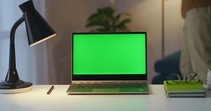 person finished work in home office, is turning off lights in room and closing laptop with green screen, closeup on working table