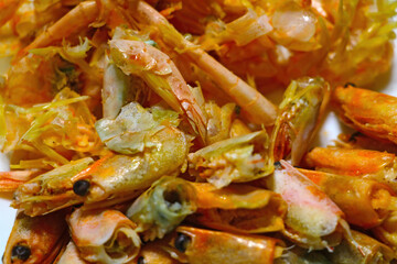 Boiled shrimp heads after eating on a plate.