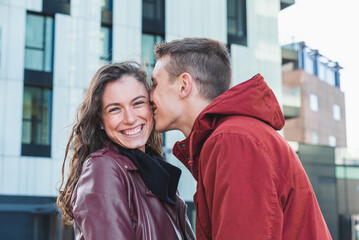 portrait of a young couple of millennials in a tender attitude, boyfriend hugs his girlfriend and...