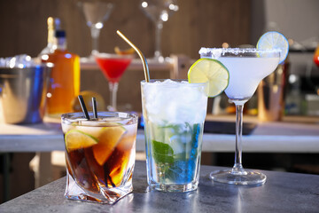 Different delicious cocktails on grey table in bar