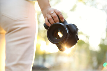 Fototapeta premium Young photographer with professional camera outdoors, closeup