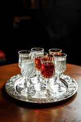 Different kinds of vermouth in small liqueur glasses on a silver tray