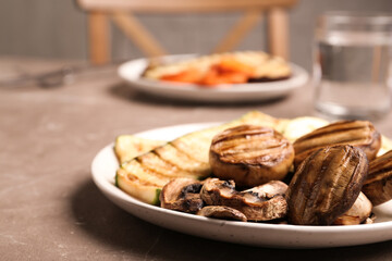 Fototapeta na wymiar Delicious grilled vegetables and mushrooms served on grey table, closeup