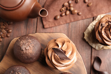 Fototapeta na wymiar Delicious chocolate muffins and cupcakes decorated with cream on wooden table, flat lay