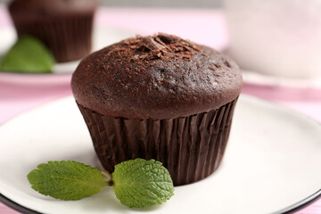 Delicious chocolate muffin with mint on plate, closeup