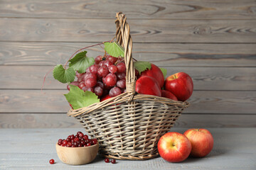 Wicker basket with fresh fruits and berries on grey wooden table