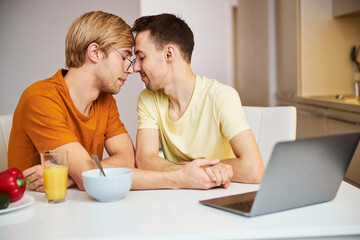 Happy gay couple holding hands and touching foreheads