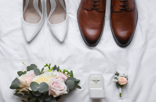 Flat lay composition with wedding shoes for bride and groom on white fabric