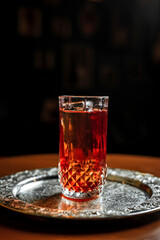 A long drink cocktail with ice in a vintage highball glass on a silver tray