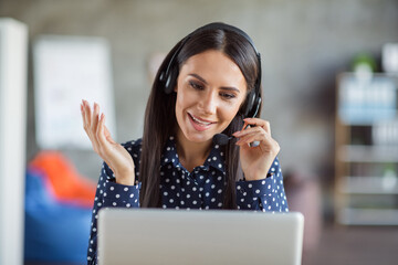 Portrait of young attractive beautiful happy positive smiling businesswoman talking in headphones...