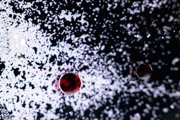 Red water ink drop on dark backgraound whit small white bubbles