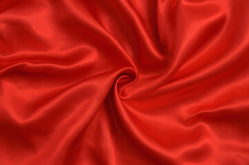 Fototapeta na wymiar Background twisted red satin fabric with folds.