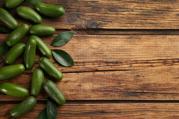 Fresh avocados with green leaves on wooden table, flat lay. Space for text