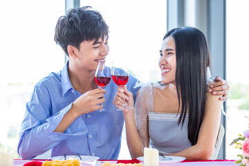 Valentine's day concept,Happy Asian Young sweet couple having romantic the Lunch with clinking toasting wine glasses at the restaurant background.