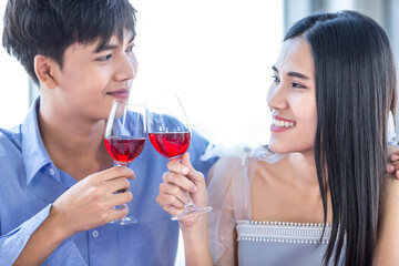 Valentine's day concept,Happy Asian Young sweet couple having romantic the Lunch with clinking toasting wine glasses at the restaurant background.