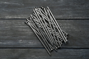 Pile of metal nails on grey wooden background, flat lay