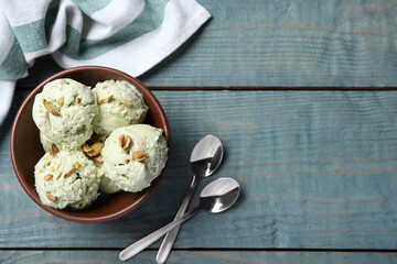 Delicious pistachio ice cream served on blue wooden table, flat lay