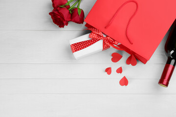 Flat lay composition with gift box and roses on white wooden background, space for text. Valentine's Day celebration