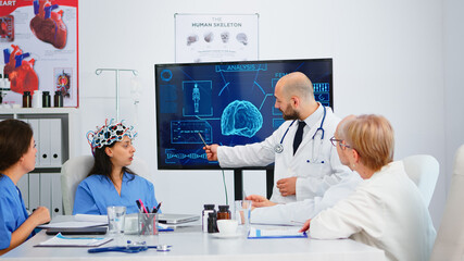 Team of doctors analysing brain functions using high tech in medical conference room, assistant...