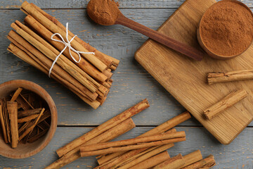 Aromatic cinnamon sticks and powder on grey wooden table, flat lay