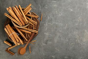Aromatic cinnamon sticks and powder on grey table, flat lay. Space for text