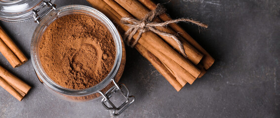Aromatic cinnamon sticks and powder on grey table, flat lay. Space for text