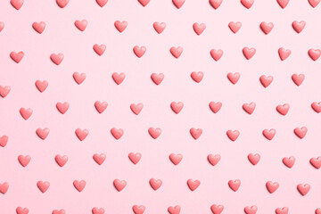 Tasty bright heart shaped sprinkles on pink background, flat lay