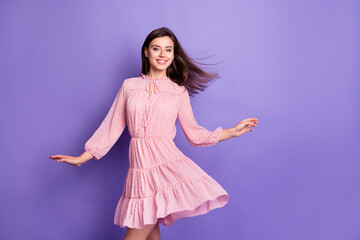 Portrait of pretty elegant cheerful girl wearing pink dress air blowing hair dancing isolated over bright violet color background