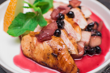 Delicious and juicy chicken with melon and berries on a white plate