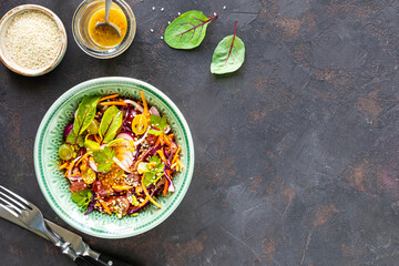 Fresh vegetable and fruit salad in a plate on a black stone background. Top view