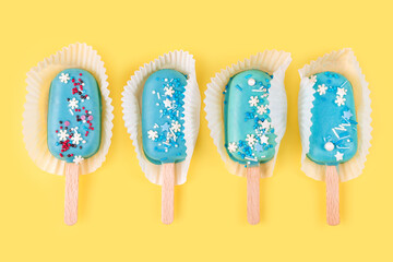 Blue mint ice cream popsicles on yellow background. Tasty and refreshing ice cream on sticks. Minimal summer concept. Flat lay
