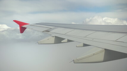 The plane flies in white clouds. View from the airplane window to the wing