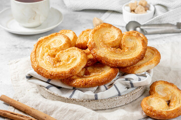 Puff. Flaky sugar Palmiers cookies in a ceramic plate on a light background. Sweet homemade cakes	