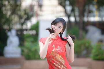 Obraz premium Action portrait beautiful Asian girl wearing Cheongsam green dress. the celebration of something in a joyful and exuberant way. Festivities and Celebration concept